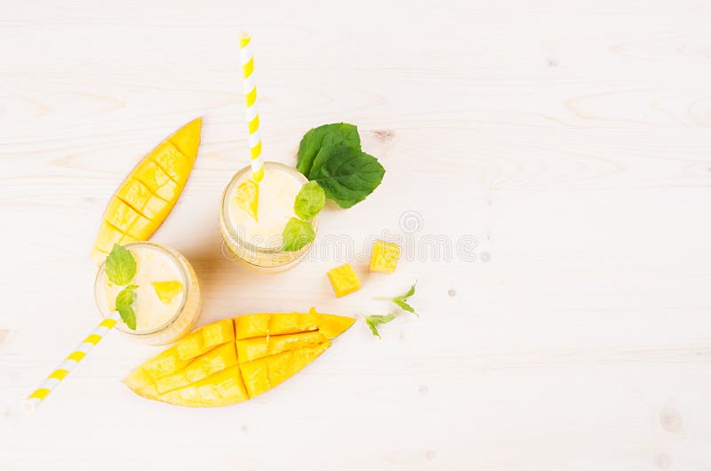 Żółty mangowy owocowy smoothie w szkle zgrzyta z słomą, nowi liście, mangowi plasterki, odgórny widok Biały drewnianej deski tło, obrazy royalty free Żółty mangowy owocowy smoothie w szkle zgrzyta z słomą, nowi liście, mangowi plasterki, odgórny widok Biały drewnianej deski tło, obrazy royalty free