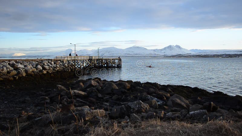 Öffnen Sie tief Fjordlandschaft mit mächtigem schneebedecktem Gebirgszug im Hintergrund und langen alten im Felsen- und Holzpier