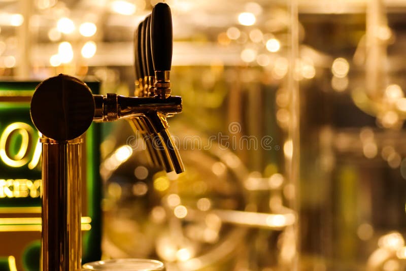 Öl för att släppa ut öl i mug med selektivt fokus och destilleri i bakgrunden av ett bryggeri