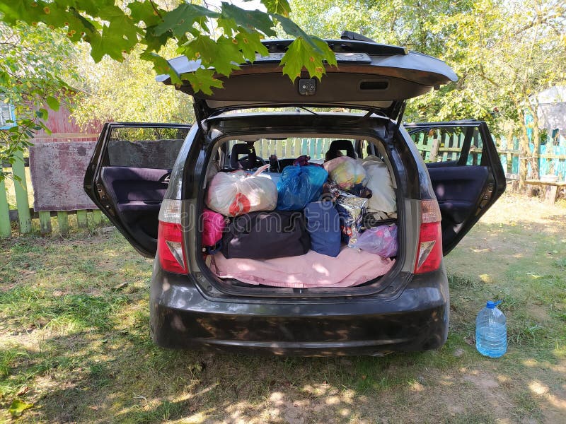 Öppna bagagehytten full av kläder på landsbygden. sommarsemester royaltyfri foto