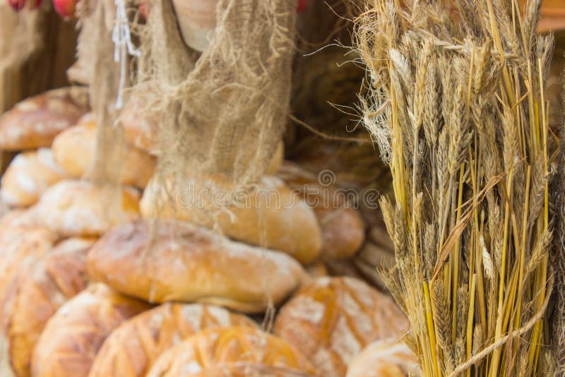 Öron av rågkorn och nytt bakade traditionella loaves av rågbröd på stall arkivbild Öron av rågkorn och nytt bakade traditionella loaves av rågbröd på stall arkivbild