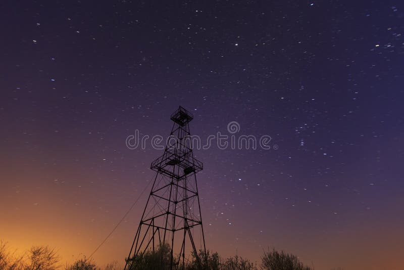 Övergiven fossila bränslenrigg på natthimmel royaltyfri bild
