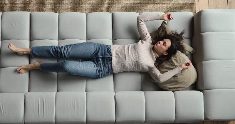 Överkomktions-vy unga utmattade kvinnor som faller ner på soffan
