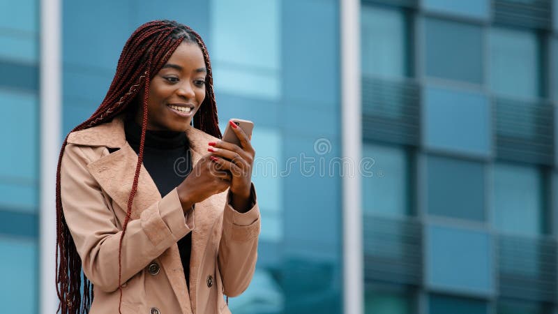 överraskad afrikansk amerikan-vinnare utomhus som läser goda nyheter om telefonfirande seger royaltyfri fotografi