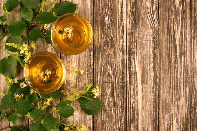 Översikt över infusionen av färskt örtte i två genomskinliga glasbägare med linda blommor och blad på royaltyfri fotografi
