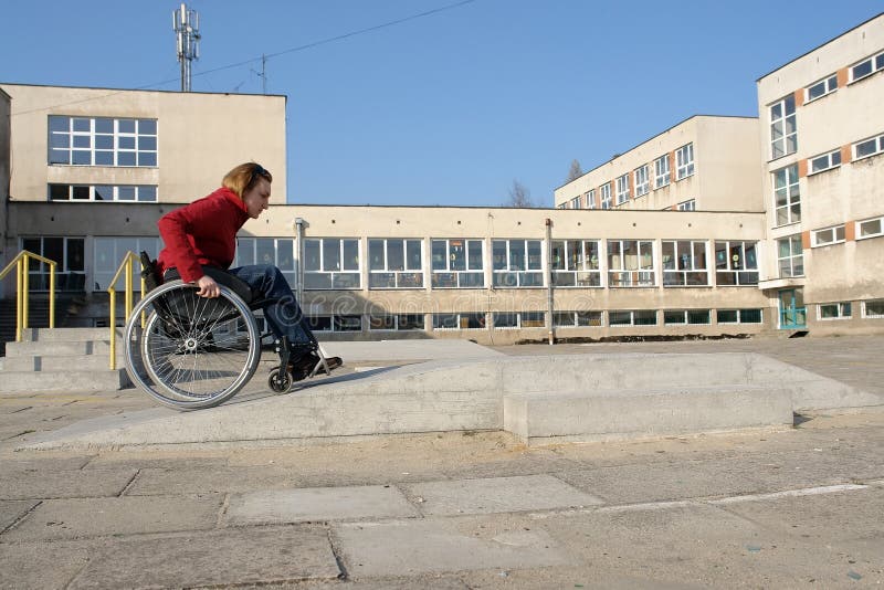 Handicapped woman practicing wheelchair riding over obstacle course for disabled. Handicapped woman practicing wheelchair riding over obstacle course for disabled