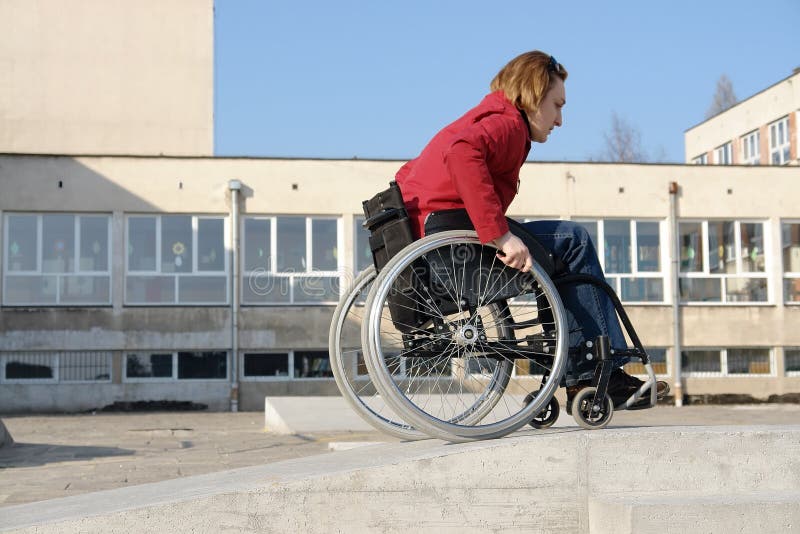 Handicapped woman practicing wheelchair riding over obstacle course for disabled. Handicapped woman practicing wheelchair riding over obstacle course for disabled