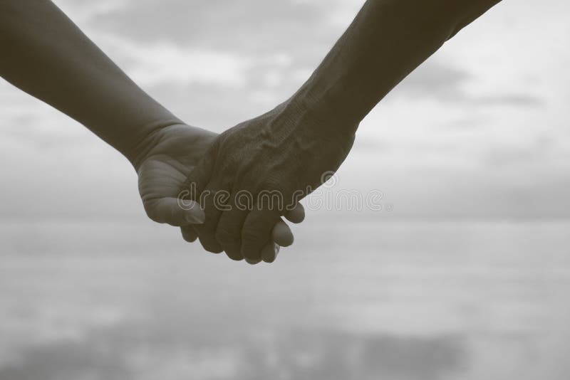 Övre hand för slut av den höga parinnehavhanden tillsammans nära sjösidan på stranden, svartvit bildfärg, filtrerad bild royaltyfri fotografi Övre hand för slut av den höga parinnehavhanden tillsammans nära sjösidan på stranden, svartvit bildfärg, filtrerad bild royaltyfri fotografi
