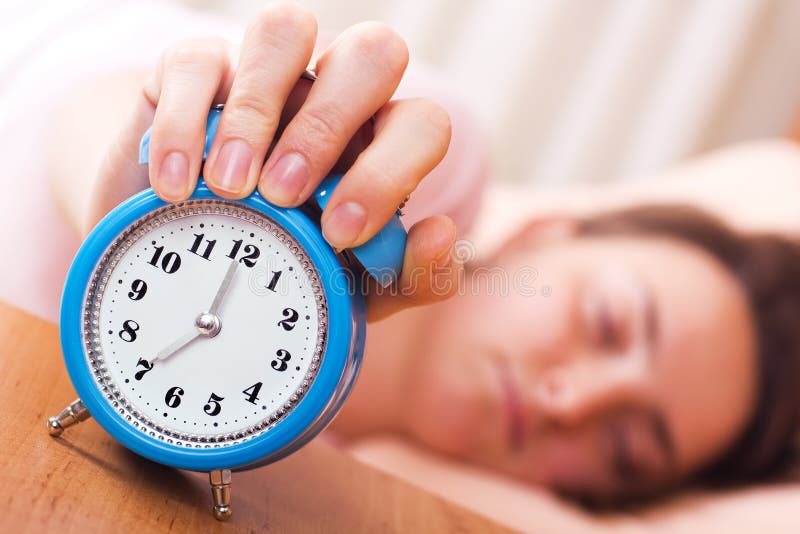 Sleeping woman shuts off an alarm clock - wake up time. Sleeping woman shuts off an alarm clock - wake up time