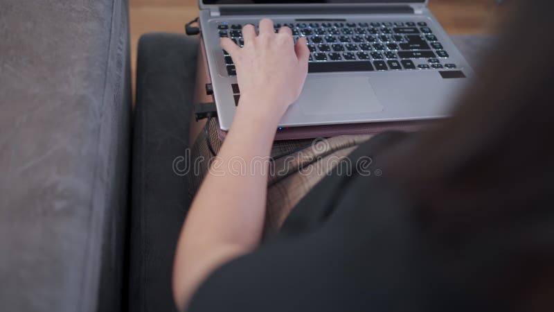 über Schulterschuss arbeitende Frau mit Computerlatop sitzend auf dem Sofa zu Hause während der Quarantäne stock video