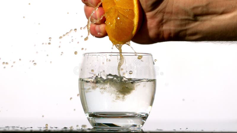 Übergeben Sie das Zusammendrücken des Safts der Orange in Glas Wasser