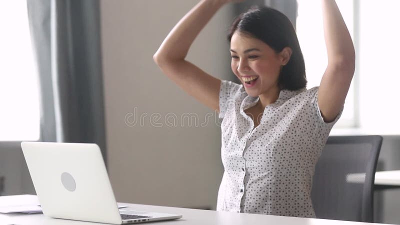 Überglücklicher glücklicher asiatischer Geschäftsfrausieger, der Laptop-Computer betrachtet