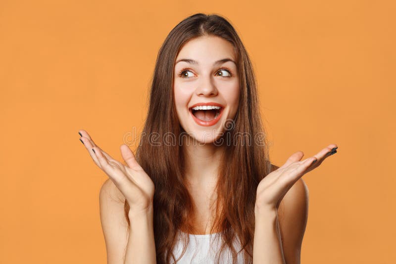 Überraschte glückliche Schönheit, die seitlich in der Aufregung schaut Lokalisiert auf orange Hintergrund stockfotos