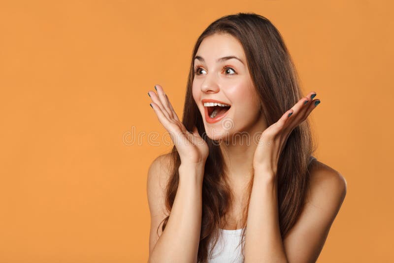 Überraschte glückliche Schönheit, die seitlich in der Aufregung schaut Lokalisiert auf orange Hintergrund stockfoto