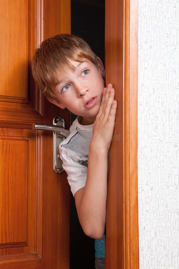 Surprised boy peeks from behind door? indoor. Surprised boy peeks from behind door? indoor