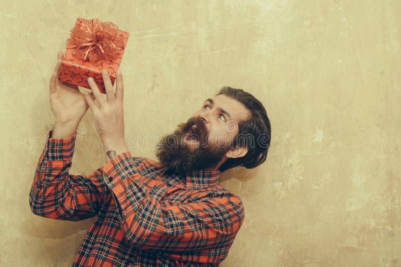Überraschter bärtiger Mann, der rote Geschenkbox mit Bogen hält stockfoto Überraschter bärtiger Mann, der rote Geschenkbox mit Bogen hält stockfoto