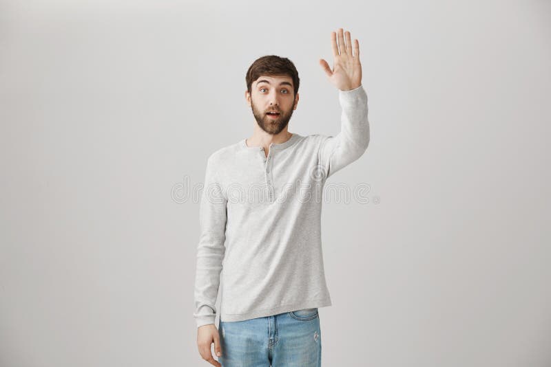 Überraschter gewöhnlicher bärtiger Kerl, der mit der angehobenen Hand steht, als ob, jemand auf der Straße wellenartig bewegend o stockfotos Überraschter gewöhnlicher bärtiger Kerl, der mit der angehobenen Hand steht, als ob, jemand auf der Straße wellenartig bewegend o stockfotos