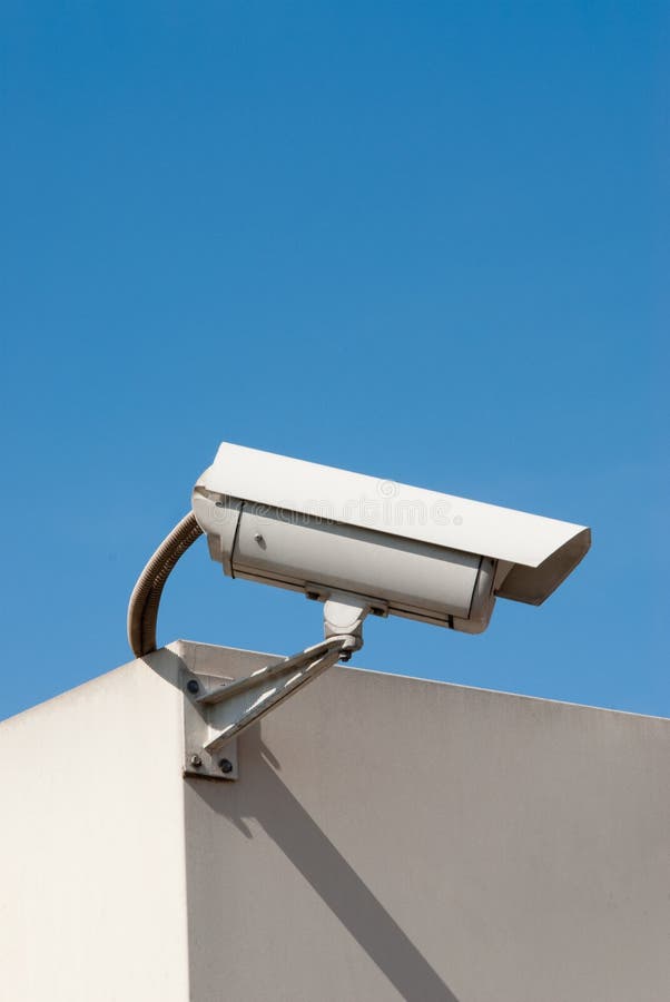 Closed circuit tv surveillance camera against a light blue sky. Closed circuit tv surveillance camera against a light blue sky