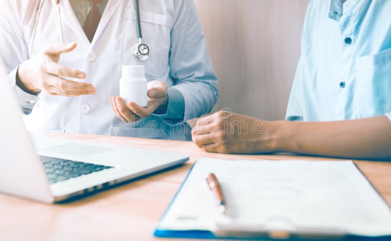 Überzeugter Doktormann, der ein Tablettenfläschchen bei der Unterhaltung mit a hält stockfotografie Überzeugter Doktormann, der ein Tablettenfläschchen bei der Unterhaltung mit a hält stockfotografie