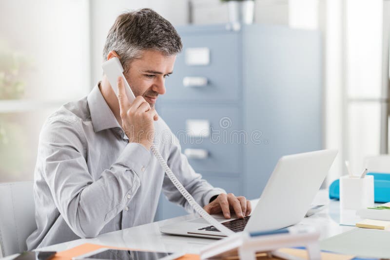 Überzeugter lächelnde Geschäftsmann und der Berater, die in seinem Büro arbeitet, hat er einen Telefonanruf: Kommunikations- und