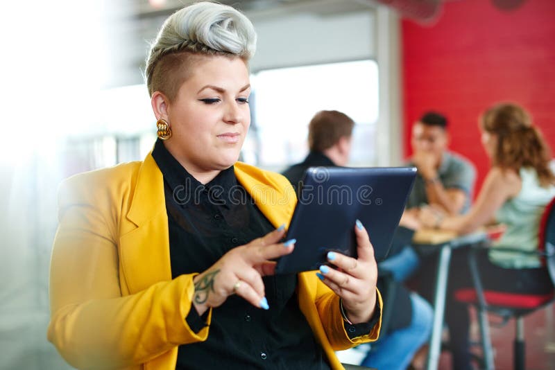 Überzeugter und nervöser weiblicher Designer, der an einer digitalen Tablette in den roten kreativen Büroräumen arbeitet lizenzfreies stockfoto Überzeugter und nervöser weiblicher Designer, der an einer digitalen Tablette in den roten kreativen Büroräumen arbeitet lizenzfreies stockfoto