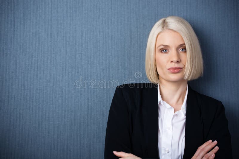 Beautiful stylish confident female business executive standing with folded arms looking at the camera with a serious expression, head and shoulders portrait. Beautiful stylish confident female business executive standing with folded arms looking at the camera with a serious expression, head and shoulders portrait