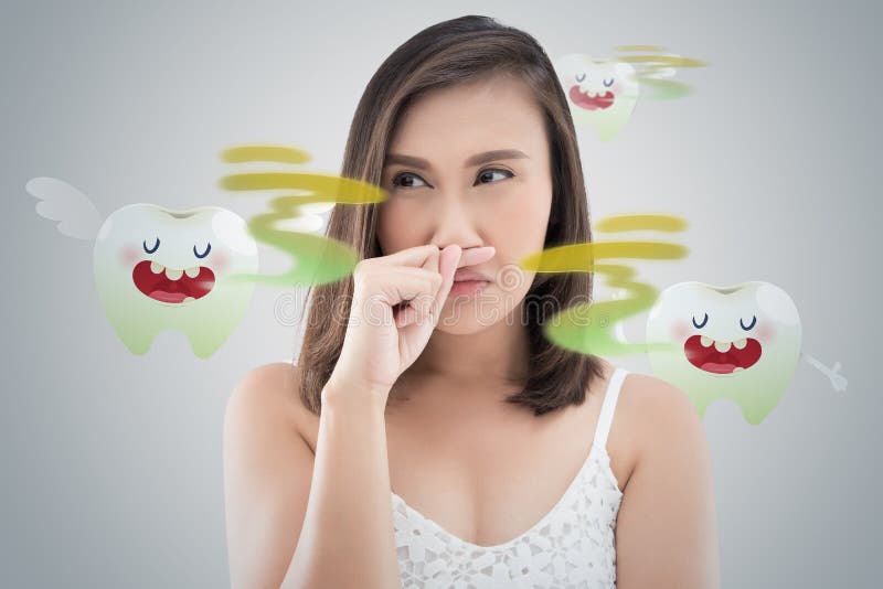 Asian woman in white dress catch her nose because of a bad smell against gray background - Halitosis or Bad breath. Asian woman in white dress catch her nose because of a bad smell against gray background - Halitosis or Bad breath