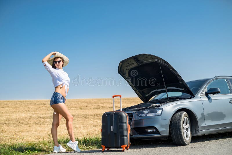 ładna dziewczyna z walizką stojącą w pobliżu samochodu i wiat na jej marzenie podróży