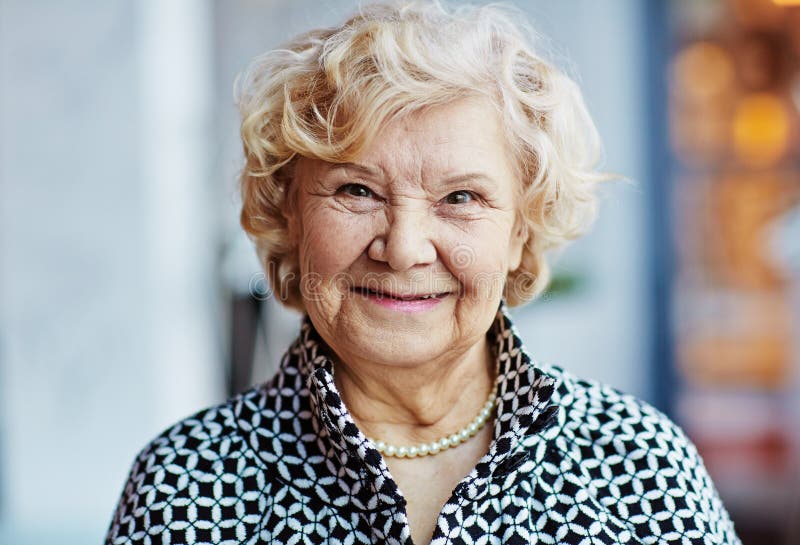 Ładna starsza kobieta przeciw zamazanemu tłu obrazy stock Ładna starsza kobieta przeciw zamazanemu tłu obrazy stock
