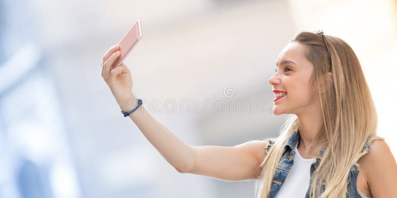 Ładny blondynka nastolatek bierze selfie z jej telefonem komórkowym Ho obraz royalty free Ładny blondynka nastolatek bierze selfie z jej telefonem komórkowym Ho obraz royalty free