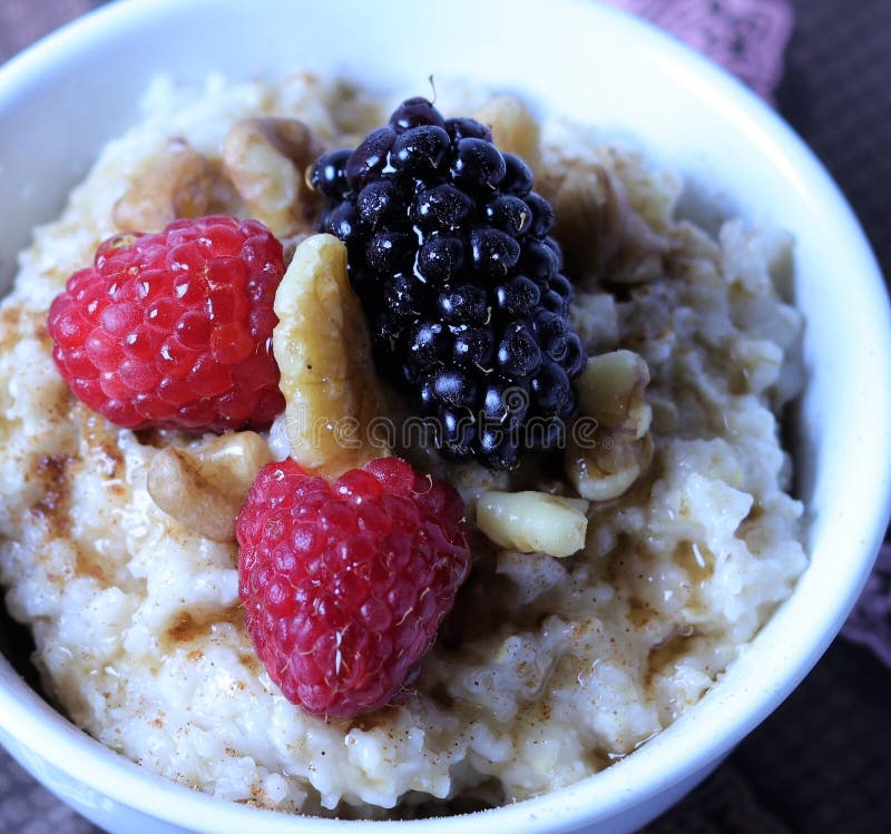 Ładny ciepły puchar oatmeal, nakrywający z malinkami i czernicami z orzechami włoskimi i dżdżą klonowy syrop zdjęcia royalty free Ładny ciepły puchar oatmeal, nakrywający z malinkami i czernicami z orzechami włoskimi i dżdżą klonowy syrop zdjęcia royalty free