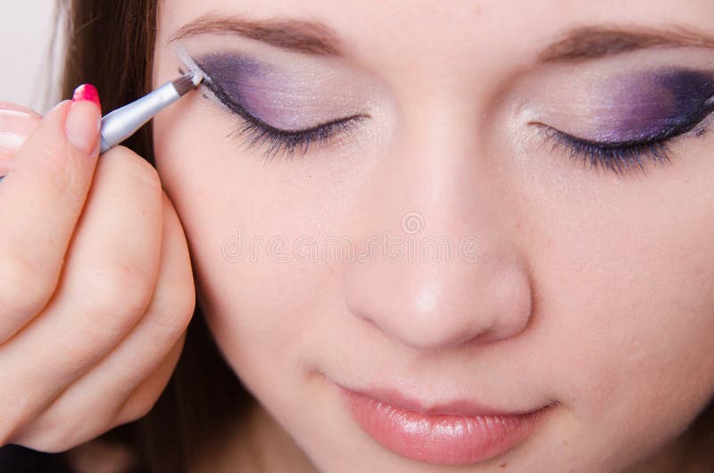 Ładny dziewczyny makeup artysta rysuje strzała na oczach obraz stock