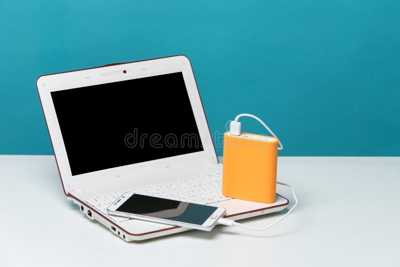 Ładuje mądrze telefon z przenośną zewnętrznie baterią na Nowożytnym laptopie w tle fotografia stock Ładuje mądrze telefon z przenośną zewnętrznie baterią na Nowożytnym laptopie w tle fotografia stock