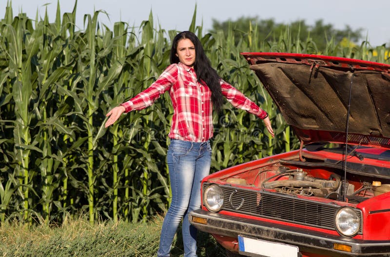 Young girl helplessly standing beside broken car at country road. Young girl helplessly standing beside broken car at country road