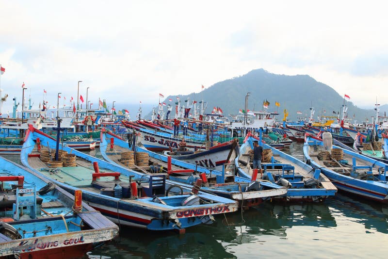 Fishing boats dock at Prigi Beach, Trenggalek, East Java, Indonesia. Blue red wooden boats with Indonesian flag. Fishing boats dock at Prigi Beach, Trenggalek, East Java, Indonesia. Blue red wooden boats with Indonesian flag.