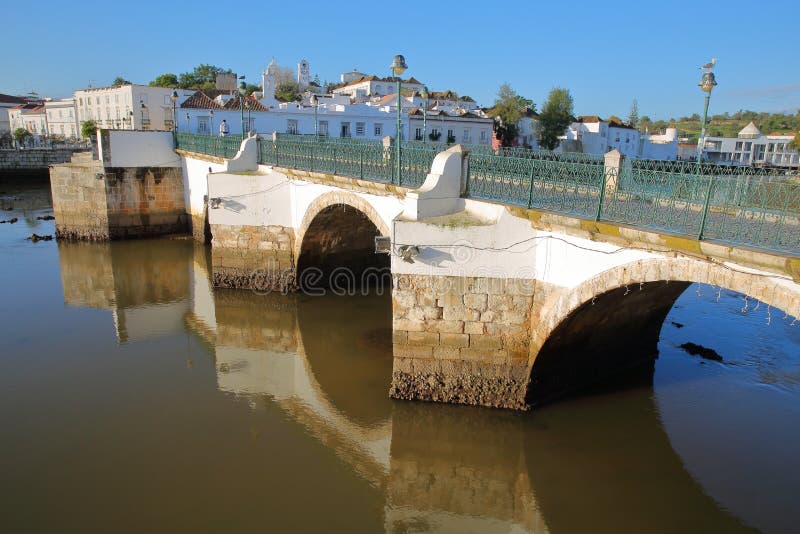 Łukowaty rzymianina most odbijał w rzecznym Rio Gilao, Tavira, Algarve, z starym miasteczkiem w tle zdjęcie stock