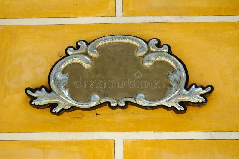 Detail of metal ornamental frame with decorative elements over yellow wall. Detail of metal ornamental frame with decorative elements over yellow wall