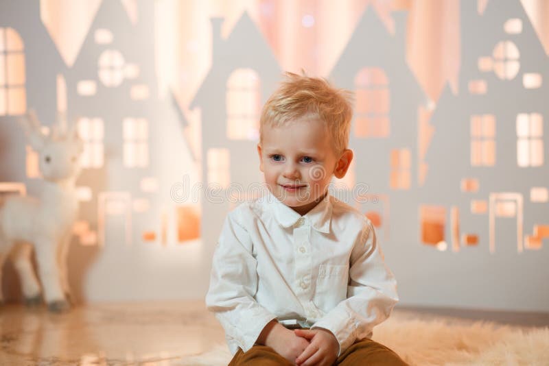 Śliczna blondynka włosy chłopiec blisko boże narodzenie zabawki papieru domów obrazy stock Śliczna blondynka włosy chłopiec blisko boże narodzenie zabawki papieru domów obrazy stock