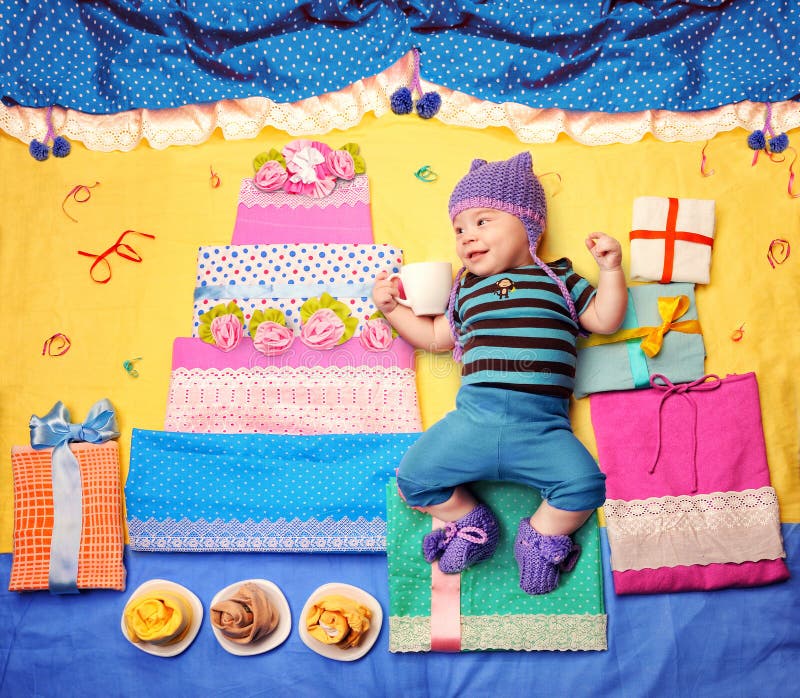 Cute smiling baby boy celebrate his first birthday with big cake and gifts, textile decoration. Cute smiling baby boy celebrate his first birthday with big cake and gifts, textile decoration