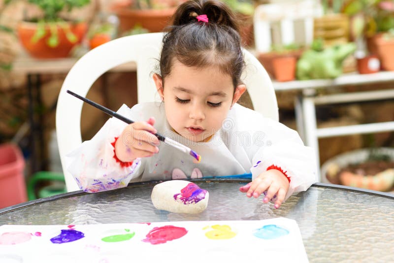 Śliczna mała dziewczynka ma zabawę, barwiący z muśnięciem, bawić się i malować, Preschooler z farbą przy ogródem zdjęcie stock Śliczna mała dziewczynka ma zabawę, barwiący z muśnięciem, bawić się i malować, Preschooler z farbą przy ogródem zdjęcie stock