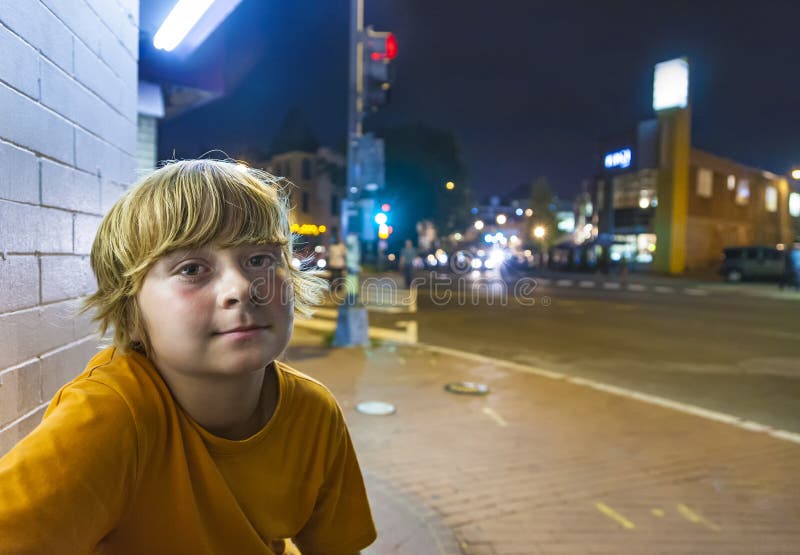 Śliczni chłopiec uśmiechy męczący nocą podczas gdy siedzący outside zdjęcie stock Śliczni chłopiec uśmiechy męczący nocą podczas gdy siedzący outside zdjęcie stock