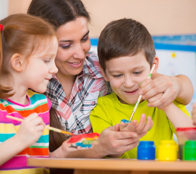 Śliczni dzieci rysuje z nauczycielem przy preschool klasą fotografia stock Śliczni dzieci rysuje z nauczycielem przy preschool klasą fotografia stock
