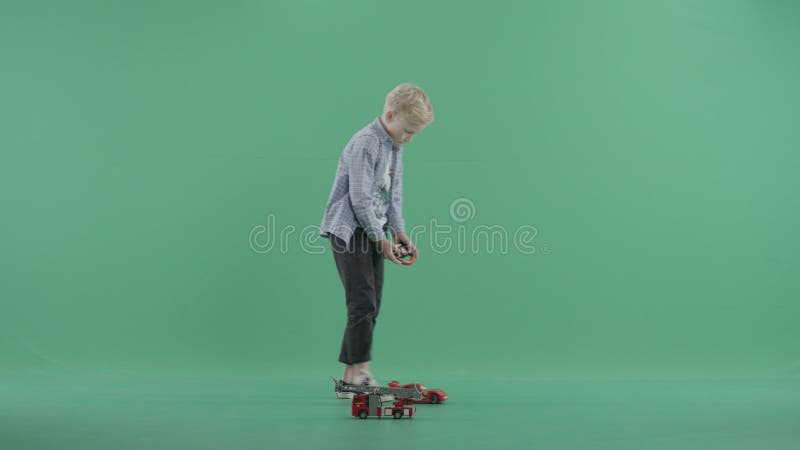 Śliczny blondynu dzieciak żegluje jego pilot do tv zabawki samochód