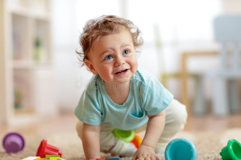 Śliczny dziecięcy dziecka czołganie na podłoga w domu, bawić się z kolorowymi zabawkami