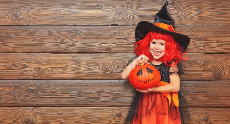 Śmieszna dziecko dziewczyna w czarownica kostiumu dla Halloween z dyniowym Ja zdjęcia stock Śmieszna dziecko dziewczyna w czarownica kostiumu dla Halloween z dyniowym Ja zdjęcia stock