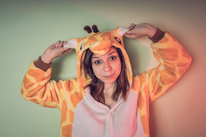 Girl in a bright children`s pajamas in the form of a kangaroo. emotional portrait of a student. costume presentation of children`s animator. Slippers in the form of cat`s paws. Girl in a bright children`s pajamas in the form of a kangaroo. emotional portrait of a student. costume presentation of children`s animator. Slippers in the form of cat`s paws.