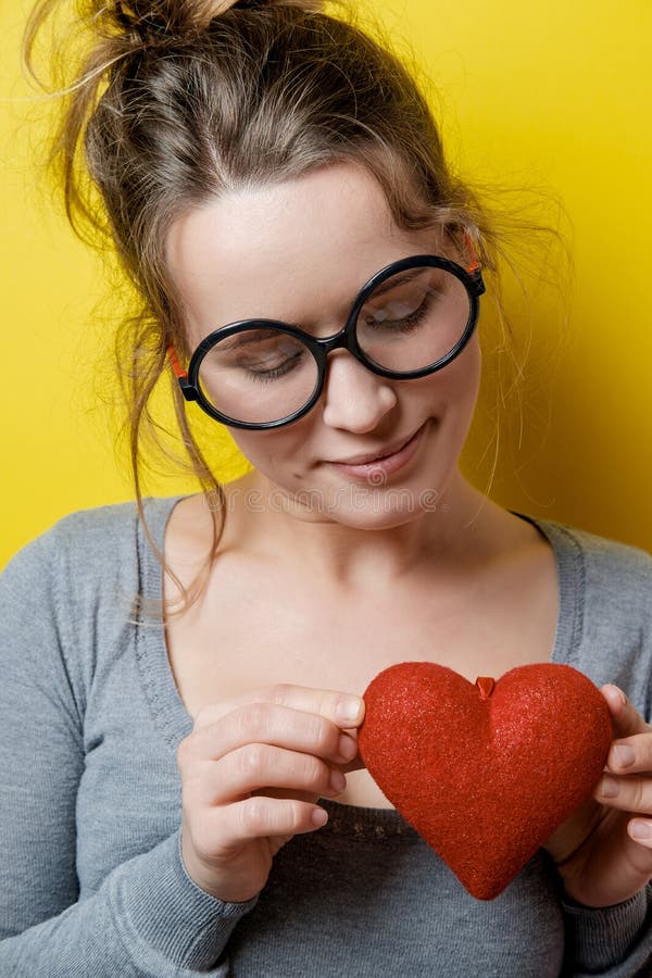 Śmieszna nerdy kobieta z czerwonym sercem na żółtym tle Valen zdjęcie royalty free Śmieszna nerdy kobieta z czerwonym sercem na żółtym tle Valen zdjęcie royalty free