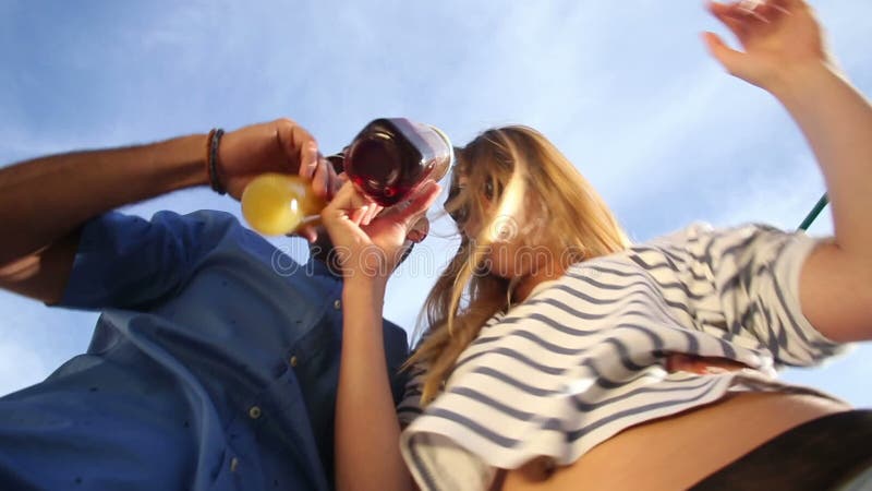 Śmieszna pijąca para patrzeje w dół przy kamerą, wznosi toast koktajle i pije