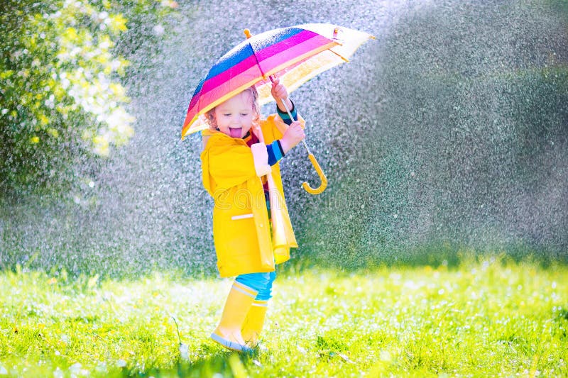 Śmieszny berbeć z parasolem bawić się w deszczu