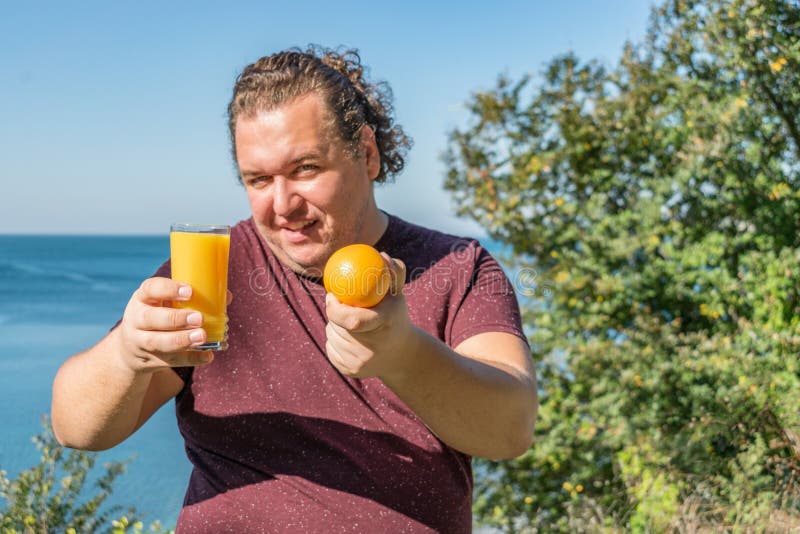 Śmieszny gruby mężczyzna pije sok i je owoc na oceanie Wakacje, ciężar strata i zdrowy łasowanie, fotografia stock Śmieszny gruby mężczyzna pije sok i je owoc na oceanie Wakacje, ciężar strata i zdrowy łasowanie, fotografia stock